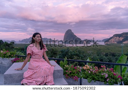 happy woman sitting infront of beautiful mountain island with twilight sky at Sametnangshe viewpoint in view of Phang Nga province at Thailand