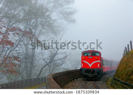 Scenery of a tourist train traveling in the heavy fog thru a railway curve on a foggy autumn day in Alishan National Scenic Area, which is a famous mountain resort and nature reserve in Chiayi, Taiwan