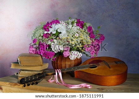Still life with a bouquet of different flowers and a musical instrument.