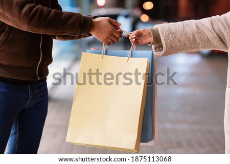Closeup of unrecognizable black man and woman holding and carrying shopping bags with blank space for template, logo or text. Young african american couple standing near mall with purchases