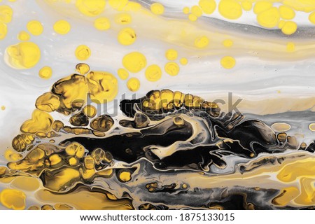 Trending colors of 2021. Flow of gray paint with yellow bubbles drops. Marble effect background or texture. Fluid Art.