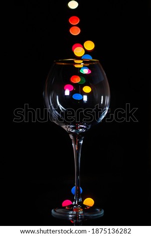 Light bokeh in the glass wine glass. In black background.