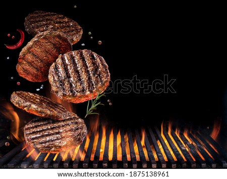 Grilled beef steaks in motion falling down on open grill. Conceptual photo of meat or barbeque cooking process.