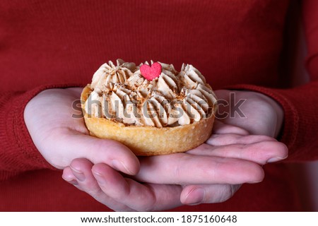 Mini Banoffee pie topped with sugar heart in woman hands. Dessert for Valentines Day