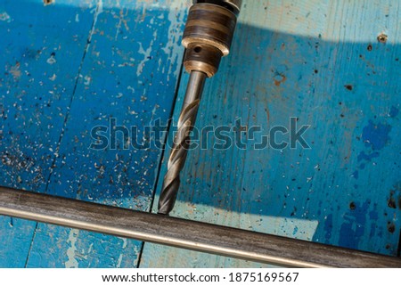 A man works with metal and an electric drill, drills holes in the metal, the work is shown close-up.