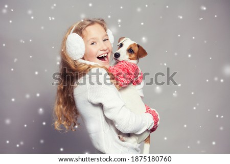 Girl with dog in winter clothes. Happy child. Studio shot