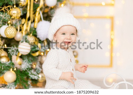 New Year's photo of a child near the Christmas tree in winter white clothes