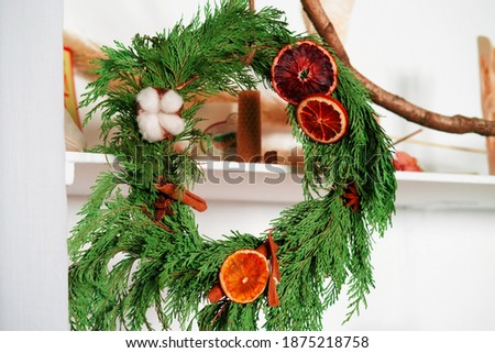 close up selective focus juniper wreath with dried orange, cinnamon sticks and cotton white background