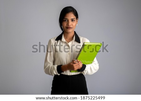 Pretty young girl holding book and posing on grey background