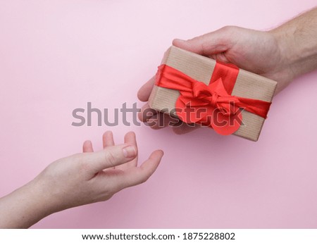  man hand gives a box with a gift to a woman hand on the pink background . selective focus .High quality photo