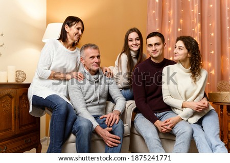 beautiful family is photographed in the New Year's decor while sitting on the couch. home comfort for christmas. new year bulbs. decoration for the new year. grandfather with baushka. children 