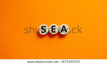 SEA symbol. Concept word 'SEA - search engine advertising' on wooden circles on a beautiful orange background. Business and search engine advertising - SEA concept. Copy space.
