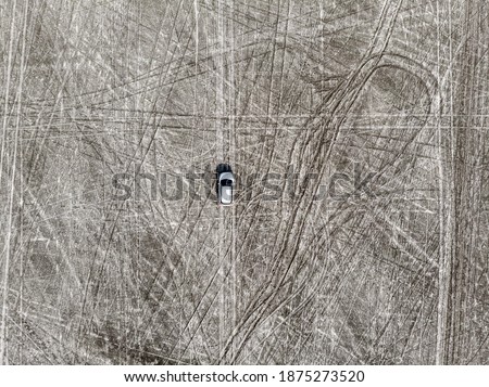Aerial view of a car in the middle of sand with tyre marks