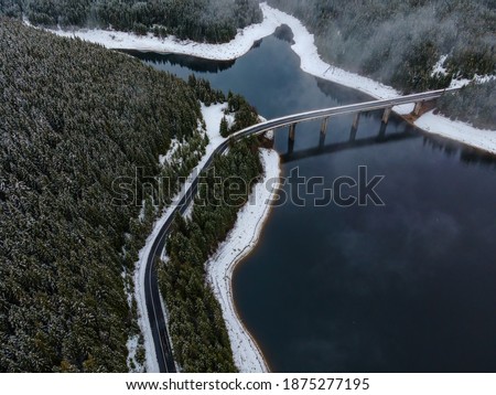 Drone photography from a high altitude of a road and a bridge crossing a mountain lake