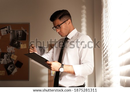 Detective with clipboard working in his office