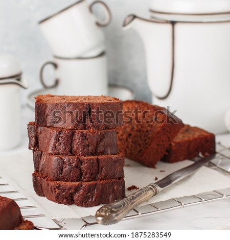 Sliced homemade chocolate pound cake loaf. Delicious dessert. A treat for tea or coffee. Breakfast on a marble table against a gray concrete wall. Selective focus, square picture