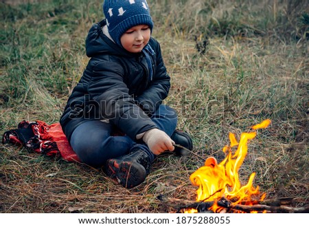 Boy in the woods near the fire.