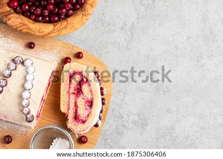 Homemade biscuit sweet roll with cranberries and cream on gray table, copy space, top view, flat lay