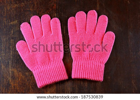 Pink knitted gloves on wooden desk 