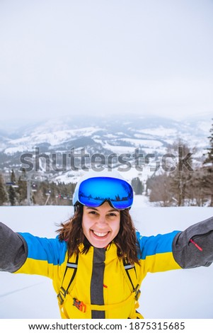 woman taking selfie in winter outfit at snowed mountain
