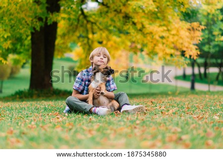 Boy hugging a dog and playing with in the fall, city park