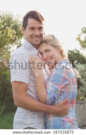 Side view of a smiling young couple embracing in the park