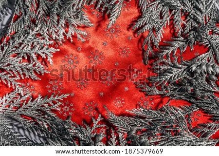 Christmas frame composition with silver thuja branches against red  background. Overhead view, flat lay with copy space.