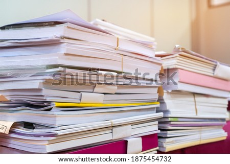 Pile of books and documents report papers waiting be managed on desk in busy office. Concept of workload in business finacial paperwork information planing