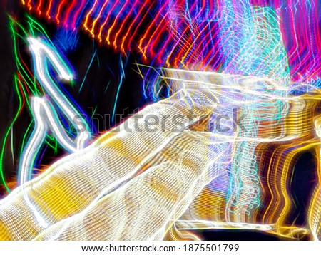 Light trails of many light-emitting diodes (LEDs) that provide festive illumination in a holiday garden at night. Long exposure with motion blur. Painting with light.