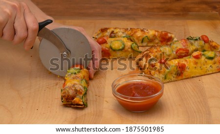 Homemade Italian flat bread focaccia with cherry tomatoes and chili pepper close up on rustic wooden background served with tomato sauce