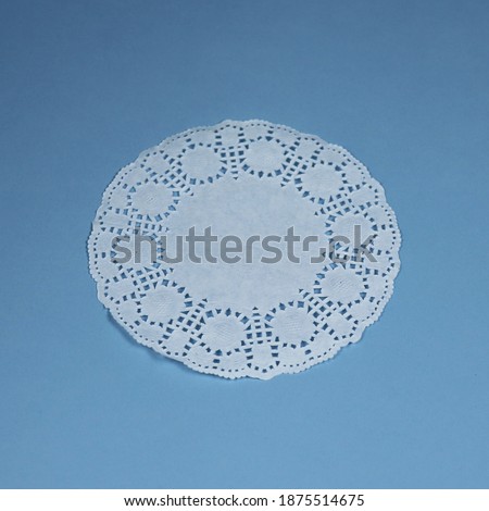 Vintage lace doily tablecloth knitted handmade grey blue colors on a white textured background.