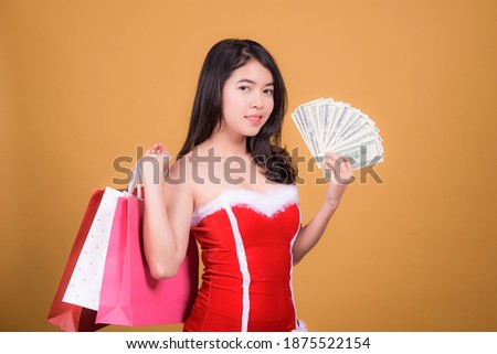 Beautiful asian woman holding a shopping bag on a yellow background Happy Christmas
