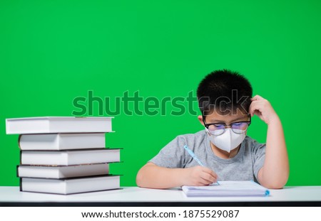 boy wearing protect mask and doing homework on green screen, child writing paper, education concept, back to school
