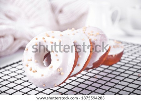 Doughnut on the baking rack glazed with white chocolate cream or icing