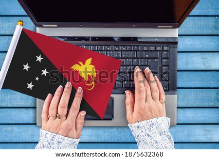 woman hands and flag of Papua New Guinea on computer, laptop keyboard 