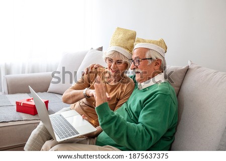 Senior couple celebrating christmas at home and having video conference and keeping a distance, during COVID-19. Seniors in Christmas video call, Online talking with family