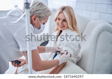 Side view portrait of happy cheerful talking with professional doctor while receiving IV infusion in beauty clinic Royalty-Free Stock Photo #1875640297