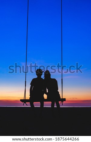 Young couple sitting on swing With a romantic silhouette style