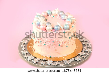 New Year's festive Christmas cake on a stand on a pink background. Christmas sweets decorated with New Year's decor and berries.