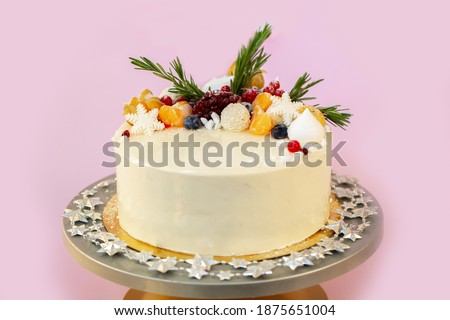 New Year's festive Christmas cake on a stand on a pink background. Christmas sweets decorated with New Year's decor and berries.