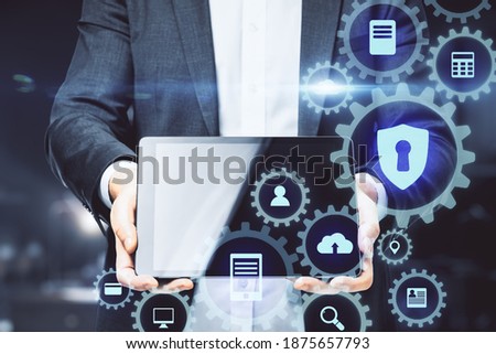 Businessman holding tablet with digital cogs interface and communication icons. Technology and innovation concept. Close up
