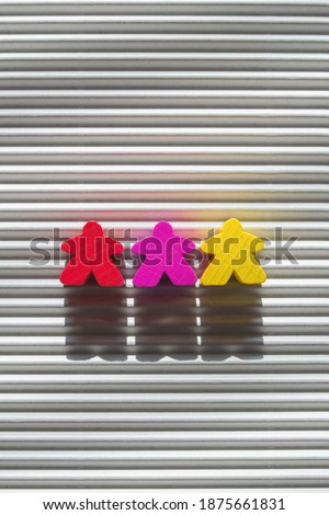 red, yellow and purple figures of people on a striped background vertical photo, three figures of people of different colors in a row