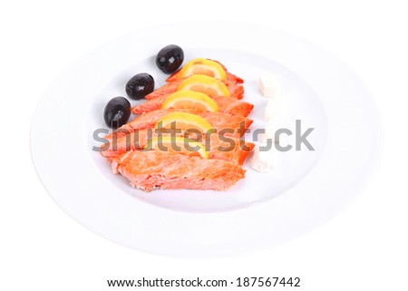 fresh roast wild pink salmon meat fillet with greek goat cheese black olives and raw lemon slices on plate isolated over white background 