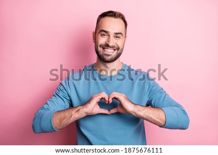 Photo of cute adorable young man dressed blue sweater showing fingers heart isolated pink color background