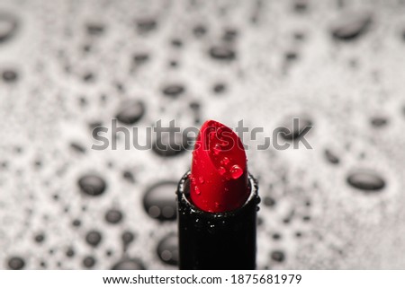Close up of red saturated lipstick with water drops. Decorative cosmetics. Visage and face makeup.