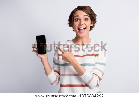 Photo of excited young lady wear striped sweater pointing holding modern gadget open mouth isolated grey color background
