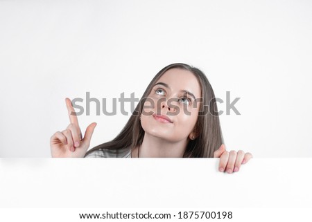 Teenage girl shows thumb up and smiles while holding white blank paper.