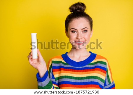 Photo of cute optimistic brunette girl show vitamins wear rainbow sweater isolated on bright yellow color background
