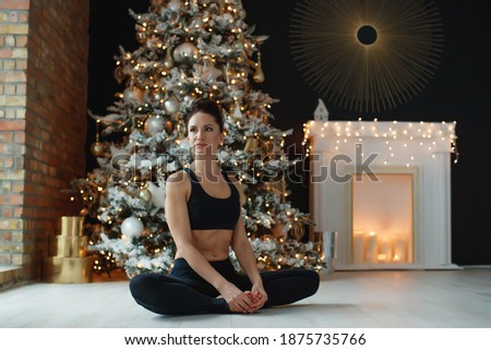 Portrait of gorgeous young woman practicing yoga indoors at Christmas time. Beautiful girl practice in the class. Calm and relax, woman happiness. High quality photo.