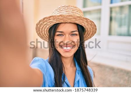 Young latin tourist girl on vacation smiling happy making selfie by the camera at the city.